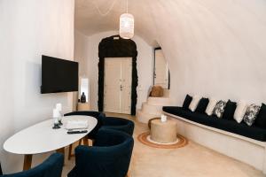 a living room with a white table and blue chairs at Three Bells Suites in Firostefani