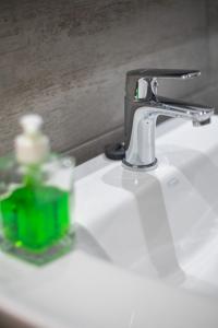 a bathroom sink with a faucet and a green bottle on it at Monoambiente Recoleta in Buenos Aires