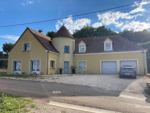 a yellow house with a car parked in the driveway at La Gibriaçoise petite chambre chez l habitant in Gevrey-Chambertin