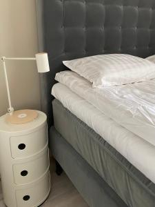 a bed with a white nightstand and a lamp on it at Apartment Leppä Rovaniemi in Rovaniemi