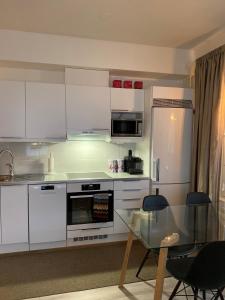 a kitchen with white cabinets and a glass table at Apartment Leppä Rovaniemi in Rovaniemi