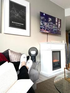 a person laying on a couch in a living room with a fireplace at Apartment Leppä Rovaniemi in Rovaniemi