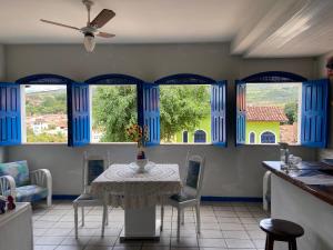 Pousada Lavramor في لينكويس: غرفة طعام مع طاولة ونوافذ زرقاء