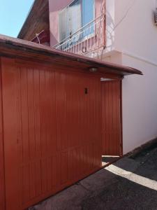 a red garage door on a building with a balcony at Sermi's House in Shkodër