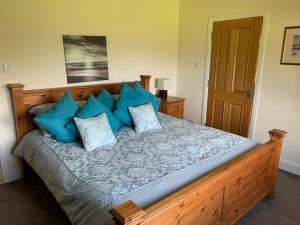 a bedroom with a wooden bed with blue pillows at Glasphein Annex Inverness in Culloden