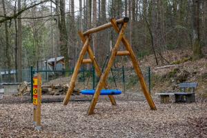 a playground with a wooden swing set in the woods at Zoo park Ranč Aladin - Glamping apartment in Mirna