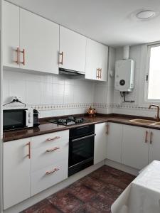 a white kitchen with white cabinets and a microwave at Big spacious penthouse next to the sea in Valencia