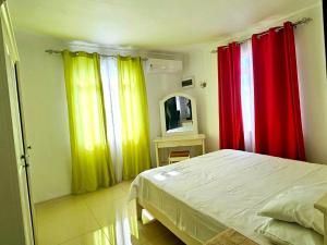 a bedroom with red and yellow curtains and a bed at White Residence in Quatre Bornes