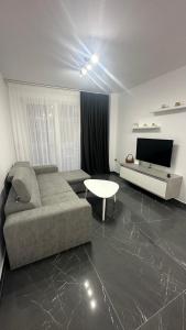 a living room with a couch and a tv at Sole apartments in Shëngjin