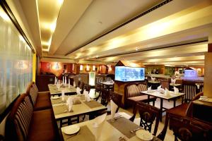 a restaurant with tables and chairs and a flat screen tv at Hotel Sitara Residency in Hyderabad