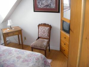 a bedroom with a bed and a chair and a tv at Auberge La Seigneurie Valcartier in Saint-Gabriel-De-Valcartier