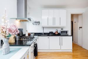 a kitchen with white cabinets and a vase of flowers at One Bedroom Near Russell Square in London