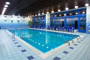 a large swimming pool with blue chairs in a building at Hotel Harmonie in Luhačovice