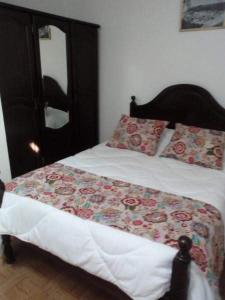 um quarto com uma cama com um cobertor floral em Apartamentos das Avós- Wimari na Nazaré