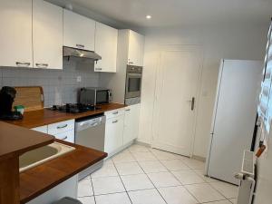 een keuken met witte kasten en een witte koelkast bij Petite maison de ville au calme in Brie-Comte-Robert