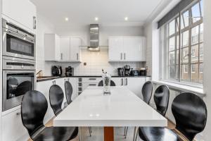 a kitchen with a white table and black chairs at Luxury Flat in London - Mayfair in London
