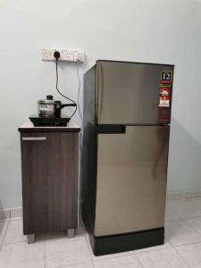 a stainless steel refrigerator next to a counter with a stove at Guan Homestay Sungai Besar 大港民宿 in Sungai Besar