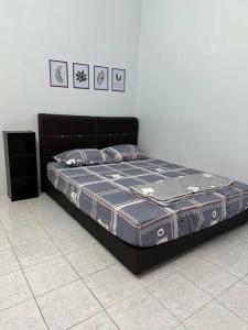 a bed in a room with a black bed frame at Guan Homestay Sungai Besar 大港民宿 in Sungai Besar