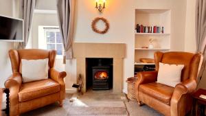 two chairs in a living room with a fireplace at Gate Cottage in Matlock