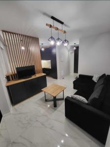 een woonkamer met een zwarte bank en een tafel bij APARTAMENT KIELCE GÓRNA 20B/4 in Kielce