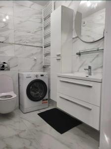 een witte badkamer met een wasmachine en een wastafel bij APARTAMENT KIELCE GÓRNA 20B/4 in Kielce