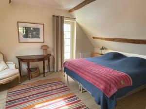 a bedroom with a bed and a table and a chair at Loue charmante maison de vacances à 10 mns de Bellême (61) 