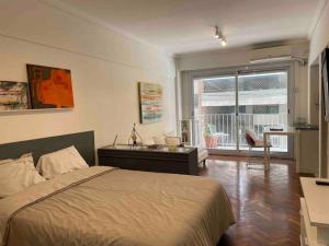 um quarto com uma cama, uma secretária e uma janela em Studio Palermo Hermoso Con Balcon em Buenos Aires