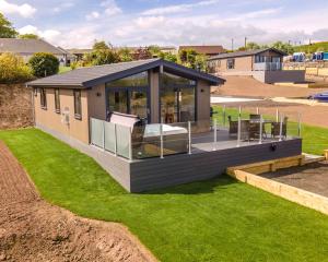 ein modulares Haus mit einer Terrasse auf einem Rasen in der Unterkunft Drumcarrow Luxury Lodges in St Andrews