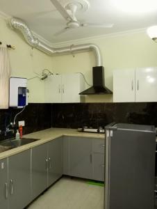 - une cuisine avec des placards blancs et un réfrigérateur en argent dans l'établissement Hare Krishna Flat, à Kharar