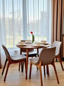 a table with chairs and a vase with a flower on it at MELODIJA apartments in Druskininkai center in Druskininkai