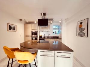 a kitchen with a counter and two yellow chairs at Stunning Spacious B.Apt. Slps.4 in London
