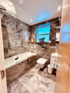 a bathroom with a tub and a toilet and a sink at Stunning Spacious B.Apt. Slps.4 in London