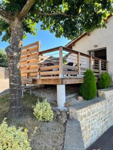 un banco de madera bajo un árbol al lado de un edificio en Appartement climatisé avec terrasse, en Cours la Ville