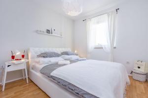 a white bedroom with a white bed and a window at Apartment Pineta in Fondole