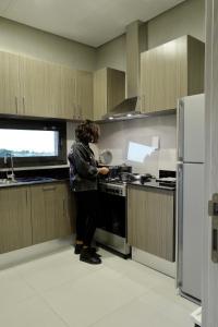 a woman standing in a kitchen preparing food at Nakheel Residence Sabah Alsalem by House living in Kuwait