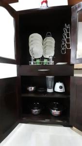 einen Küchenschrank mit Geschirr und Geräten in der Unterkunft Apartahotel Zamflor in Puerto Asís