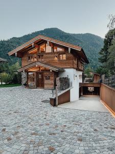 uma casa grande com uma entrada de pedra em frente em Chalet Alpin mit privatem Whirlpool und Sauna em Bayrischzell