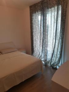 Schlafzimmer mit einem Bett und einem Fenster mit Vorhängen in der Unterkunft B&B PORTELLO Le Terrazze 2 in Mailand