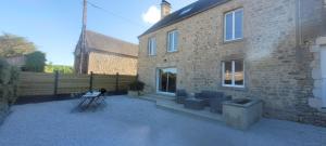 a brick house with blue chairs in front of it at Belle maison en pierre avec cour in Huberville