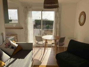 a living room with a couch and a table and a window at Studio vue sur l’océan in Saint-Brevin-les-Pins