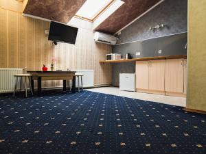 Großes Zimmer mit einem Tisch und einem TV. in der Unterkunft Hotel UNENEGE in Nizhyn