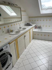 ein Badezimmer mit zwei Waschbecken, einer Badewanne und einem Spiegel in der Unterkunft Schöne Ferienwohnung im Voralpenland in Pfaffing