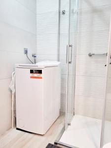 a bathroom with a shower and a white refrigerator at Los Cristianos Ljus in Arona