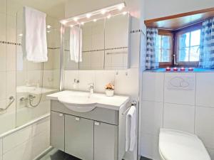 a white bathroom with a sink and a toilet at Holiday flat with Jacuzzi for 6 persons-Lenzerheide in Lenzerheide