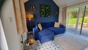 um sofá azul numa sala de estar com uma janela em Hallegan Annexe with Private Garden and Woodland em Camborne