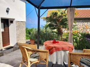 eine Terrasse mit einem Tisch, Stühlen und einem Sonnenschirm in der Unterkunft kuca Maria in Veprinac