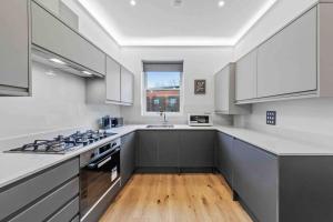 a kitchen with white cabinets and a stove top oven at 2BR flat for 6 in Central London LR2 in London
