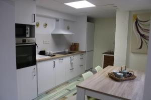 a kitchen with white cabinets and a wooden table at Casa Remes in Sagunto