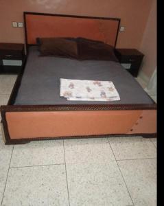 a bed with a wooden headboard with a blanket on it at Ferme fes in Fès +3 photos