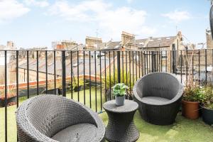 2 rieten stoelen en een tafel op een balkon bij Cozy 2 Bedroom / Earls Court / Balcony in Londen